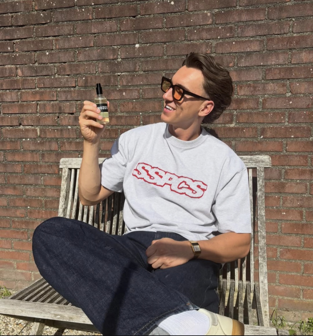 Man op een bankje in de zon met een flesje Nozes